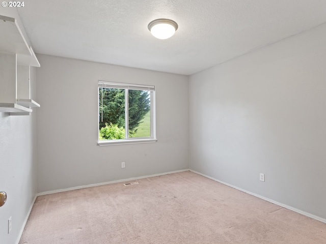 carpeted empty room featuring a textured ceiling