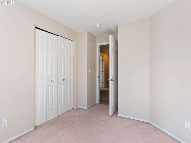 unfurnished bedroom with light carpet and a closet