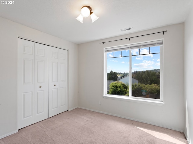 unfurnished bedroom featuring light colored carpet and a closet