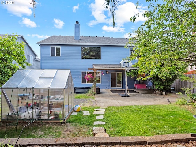 back of house featuring a lawn, an outbuilding, and a patio