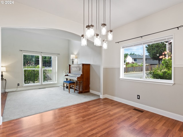 unfurnished room featuring wood-type flooring, a wealth of natural light, and a chandelier