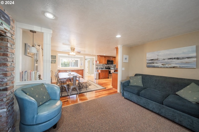 living room with a textured ceiling, light hardwood / wood-style floors, and ceiling fan