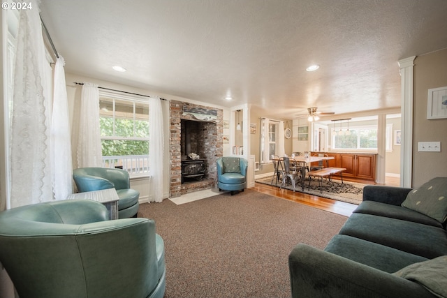 living room featuring a wood stove, ceiling fan, hardwood / wood-style floors, and a textured ceiling