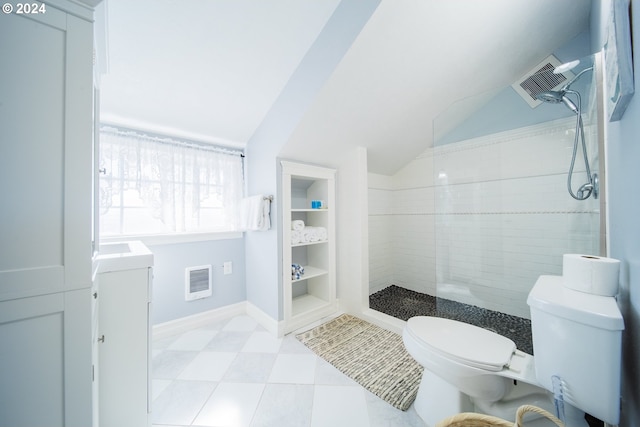 bathroom with vanity, vaulted ceiling, toilet, tiled shower, and washer / clothes dryer