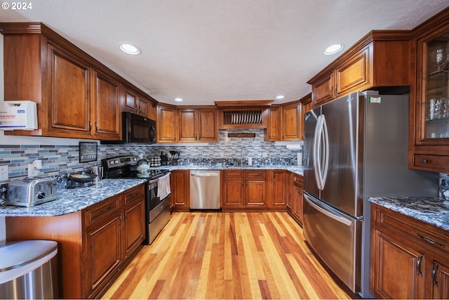 kitchen featuring sink, decorative backsplash, light stone countertops, light hardwood / wood-style floors, and stainless steel appliances