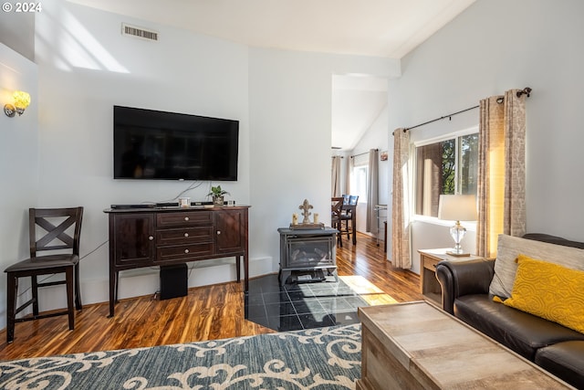 living room with vaulted ceiling, a wood stove, and hardwood / wood-style flooring