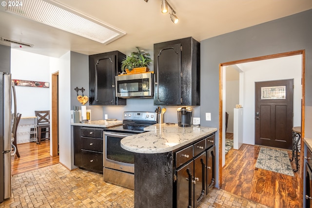 kitchen featuring stainless steel appliances, light stone counters, and light wood-type flooring