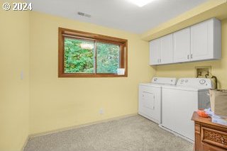 laundry room featuring cabinets, independent washer and dryer, and light carpet