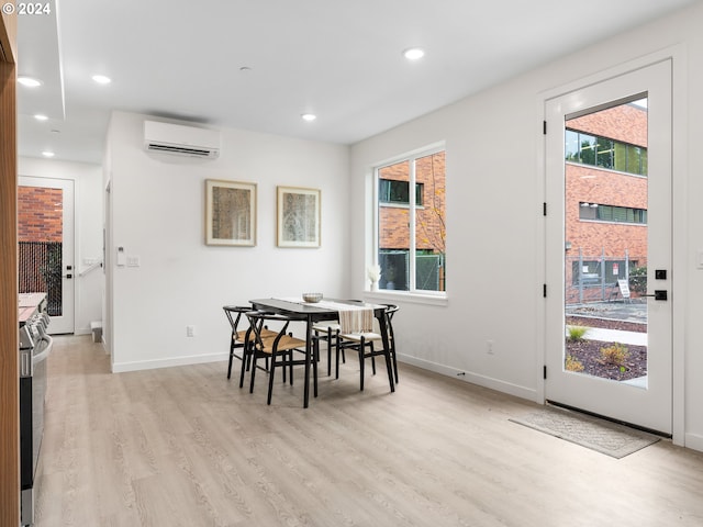 dining space with a wall unit AC and light hardwood / wood-style flooring