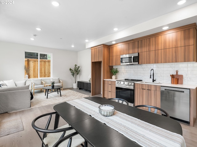 kitchen with light hardwood / wood-style floors, sink, stainless steel appliances, and tasteful backsplash