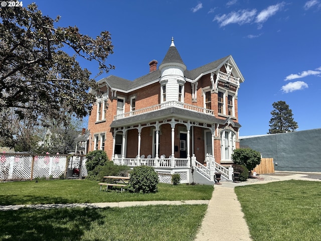 victorian-style house featuring a porch and a front lawn