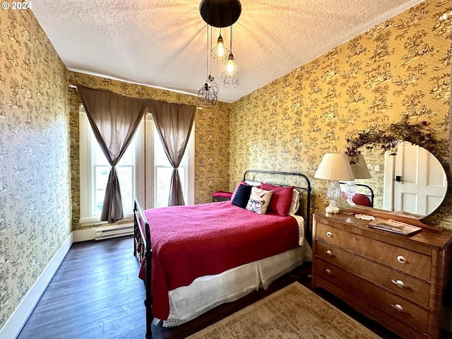 bedroom with a textured ceiling, baseboard heating, and dark wood-type flooring