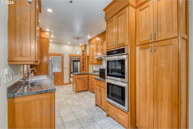 kitchen featuring dark stone counters, sink, light tile patterned floors, and stainless steel double oven