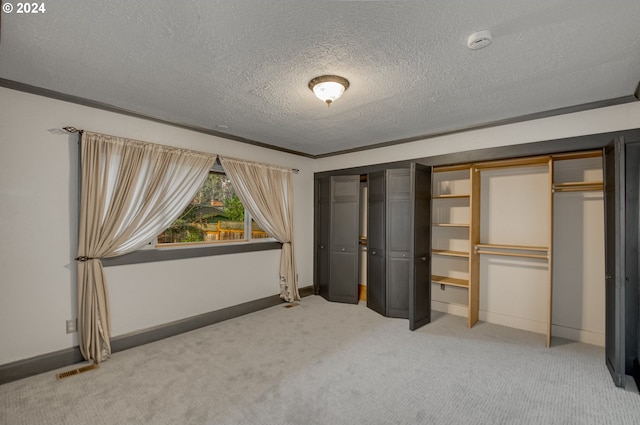 unfurnished bedroom with multiple closets, crown molding, carpet, and a textured ceiling