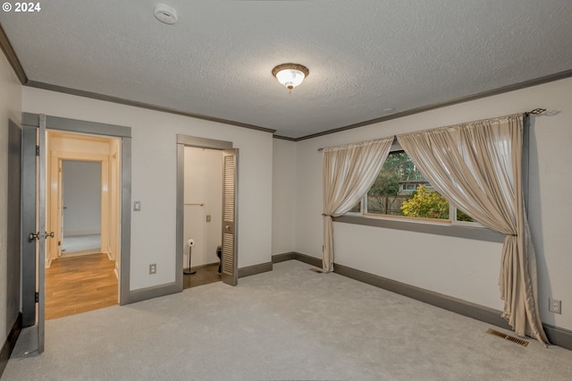 unfurnished bedroom with carpet flooring, ornamental molding, and a textured ceiling