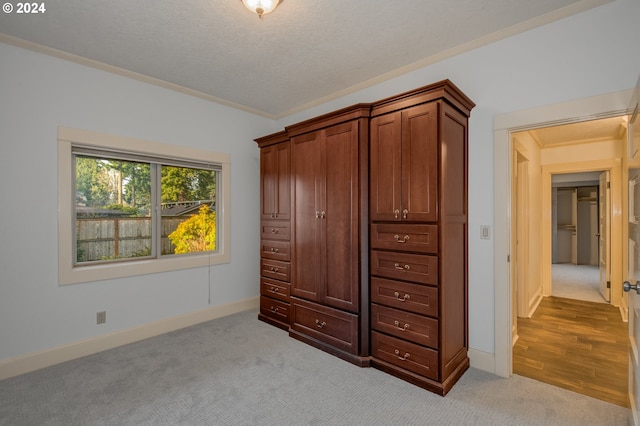 unfurnished bedroom with a textured ceiling, light colored carpet, and ornamental molding