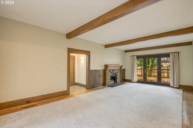 unfurnished living room featuring a stone fireplace, beamed ceiling, and light hardwood / wood-style floors