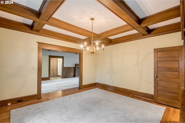 spare room with a notable chandelier, beam ceiling, wood-type flooring, and coffered ceiling