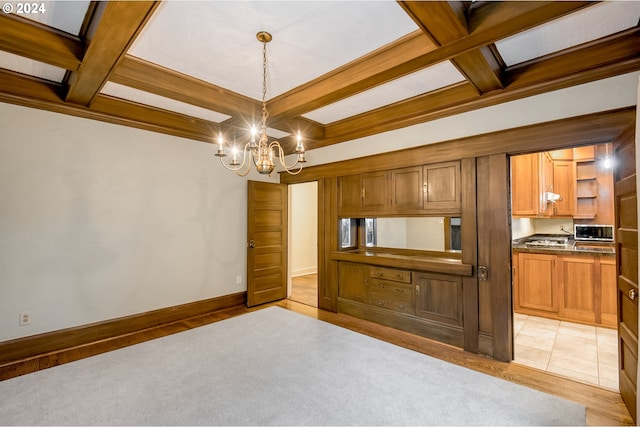 interior space with beamed ceiling, light wood-type flooring, an inviting chandelier, and coffered ceiling