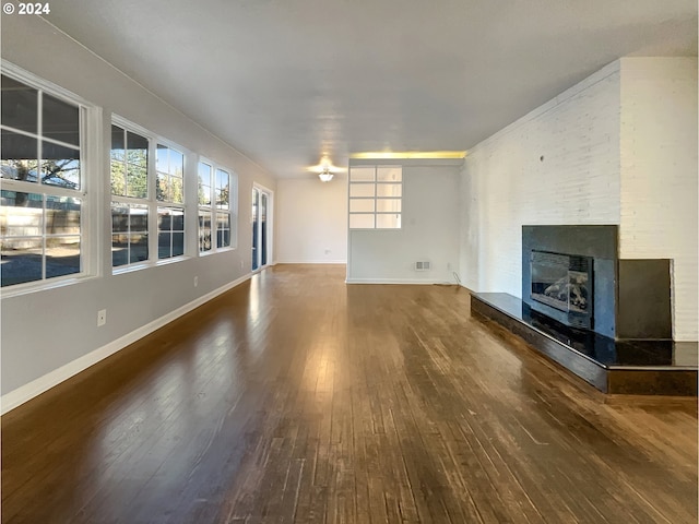 unfurnished living room featuring a fireplace, dark hardwood / wood-style floors, and plenty of natural light