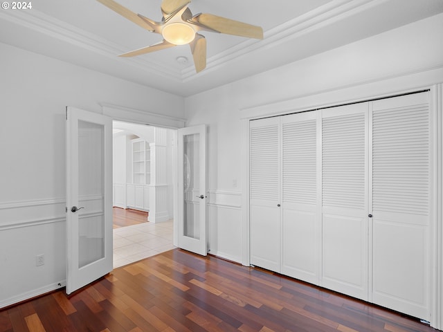 unfurnished bedroom with wood-type flooring, a raised ceiling, french doors, and ceiling fan