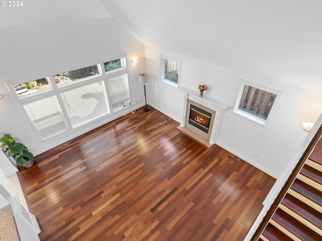 unfurnished living room with vaulted ceiling, plenty of natural light, and dark hardwood / wood-style floors