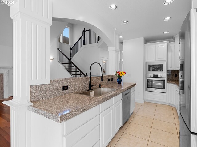 kitchen featuring hanging light fixtures, stainless steel appliances, light tile patterned floors, a chandelier, and white cabinets