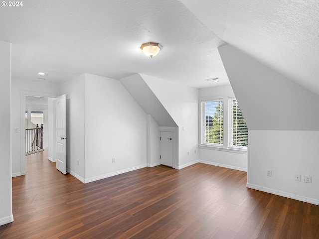 bonus room featuring vaulted ceiling, a textured ceiling, and dark hardwood / wood-style floors