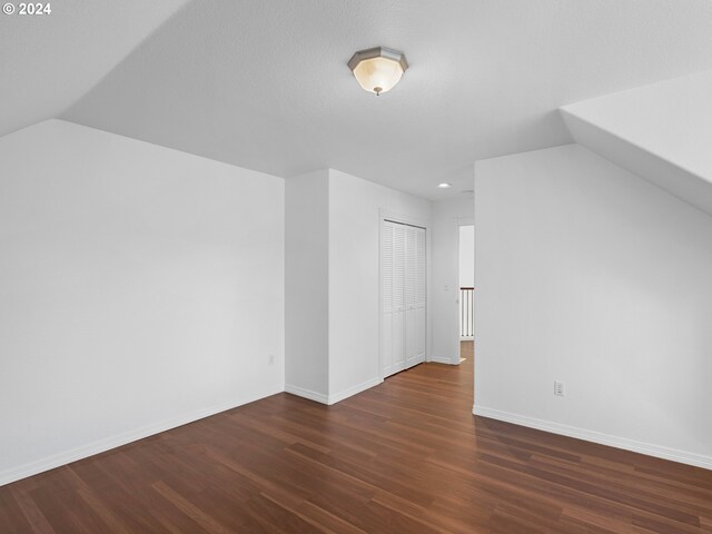 bonus room featuring a textured ceiling, dark hardwood / wood-style flooring, and lofted ceiling