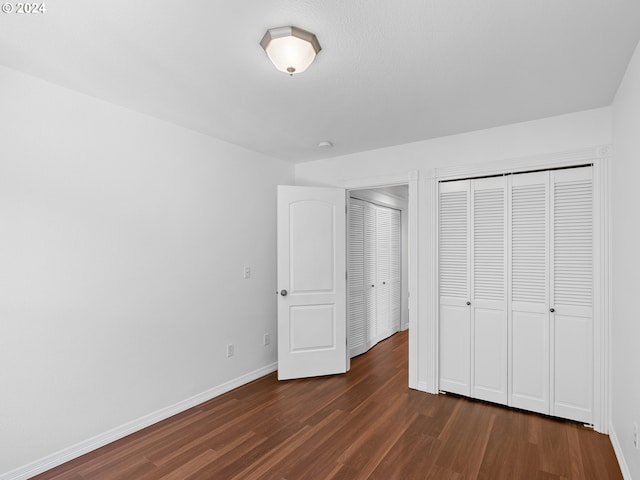 unfurnished bedroom with a closet and dark hardwood / wood-style flooring