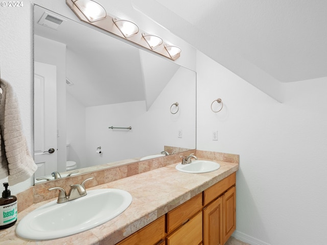 bathroom with vanity, toilet, and lofted ceiling