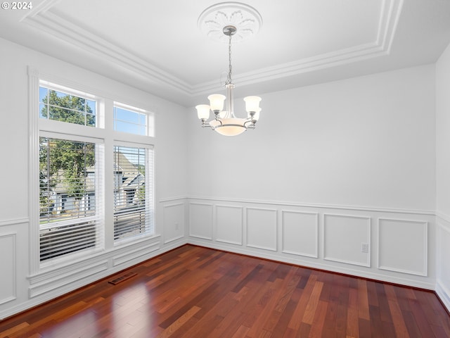 spare room featuring a raised ceiling, dark wood-type flooring, and a notable chandelier