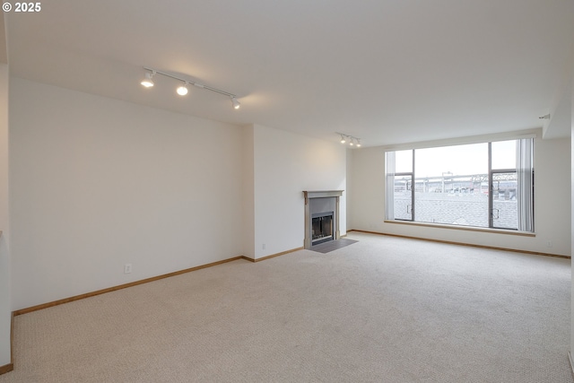 unfurnished living room with rail lighting and light colored carpet