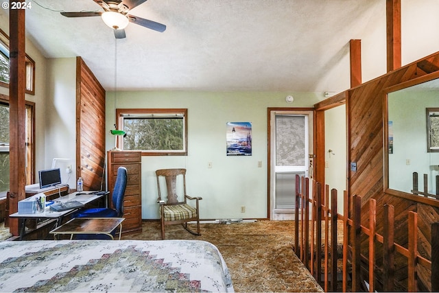 bedroom with ceiling fan, wooden walls, and a textured ceiling