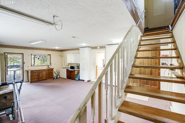 stairway with a textured ceiling and carpet