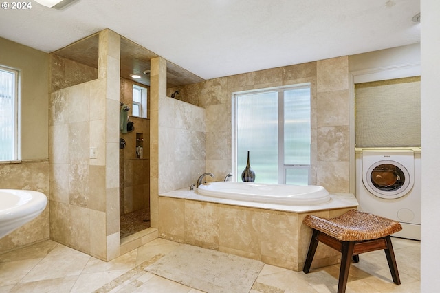 bathroom featuring tile flooring, tile walls, shower with separate bathtub, and washer / dryer