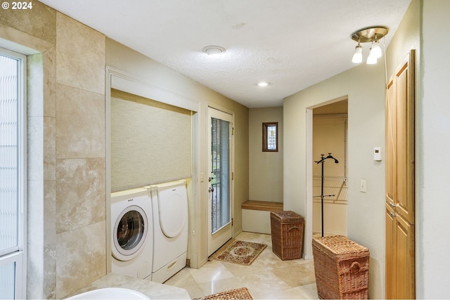 clothes washing area with light tile flooring and washer and dryer