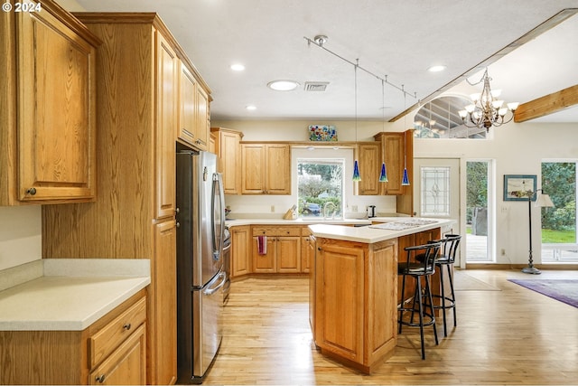 kitchen with a kitchen bar, light hardwood / wood-style flooring, stainless steel fridge, and a wealth of natural light