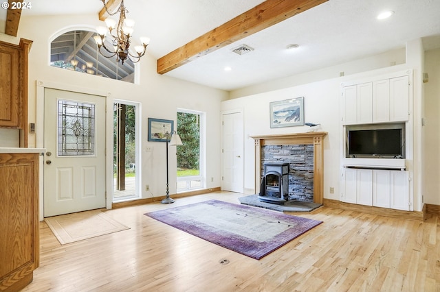 entryway featuring beamed ceiling, light hardwood / wood-style flooring, a chandelier, and a stone fireplace