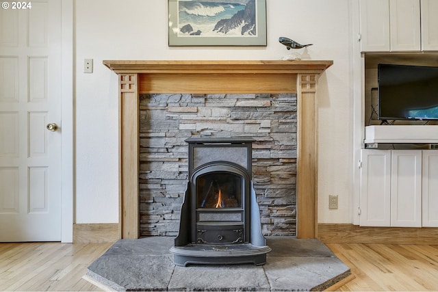 room details with light wood-type flooring, a wood stove, and a fireplace