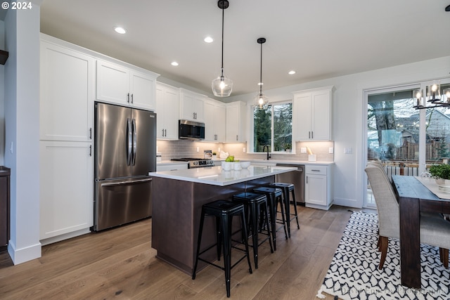 kitchen featuring a kitchen island, appliances with stainless steel finishes, a chandelier, light hardwood / wood-style flooring, and white cabinetry