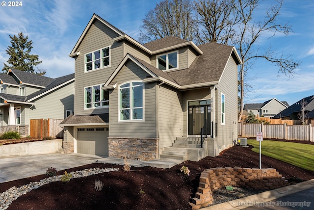 craftsman-style house with central air condition unit, a front lawn, and a garage