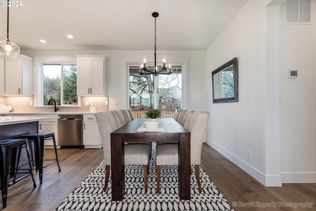 dining room with hardwood / wood-style floors and an inviting chandelier