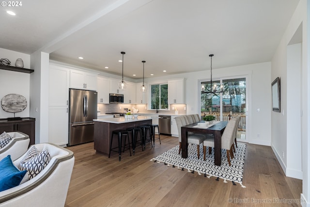 dining area with light hardwood / wood-style floors and a notable chandelier