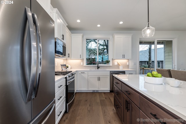 kitchen featuring dark hardwood / wood-style floors, pendant lighting, stainless steel appliances, tasteful backsplash, and white cabinetry