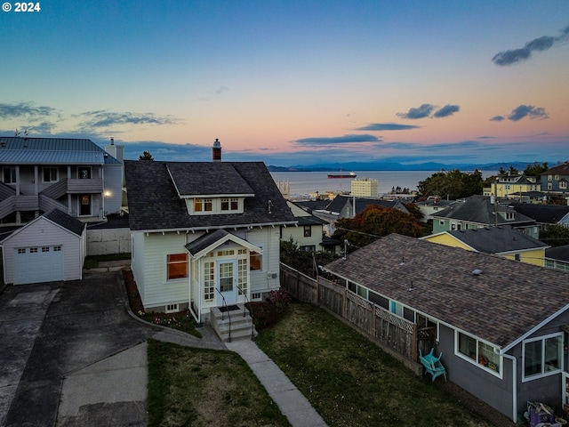 view of front of house featuring a water view, a garage, a yard, and an outdoor structure