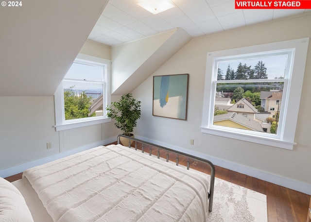 bedroom with lofted ceiling, multiple windows, and hardwood / wood-style flooring