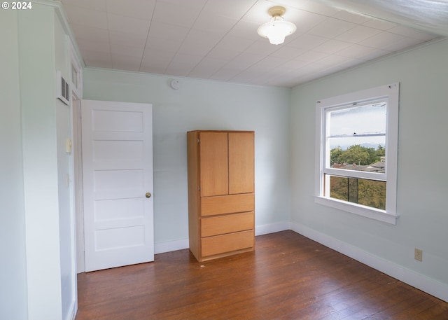 unfurnished bedroom with crown molding and dark hardwood / wood-style flooring