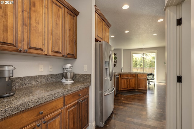 kitchen featuring dark hardwood / wood-style floors, stainless steel fridge, hanging light fixtures, and a textured ceiling