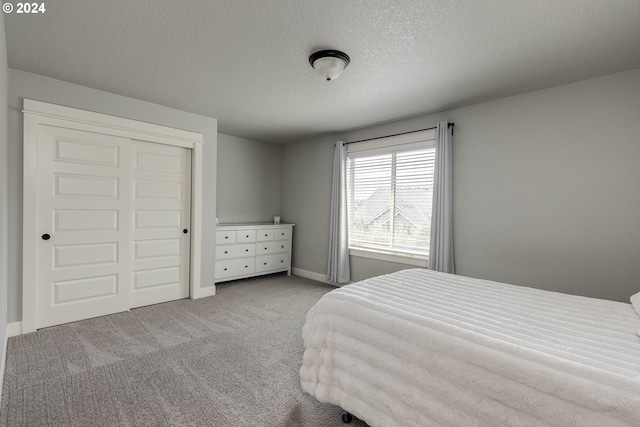 carpeted bedroom featuring a closet and a textured ceiling